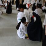 An adult student testing lightly on a younger student, to find their coordination (stability)